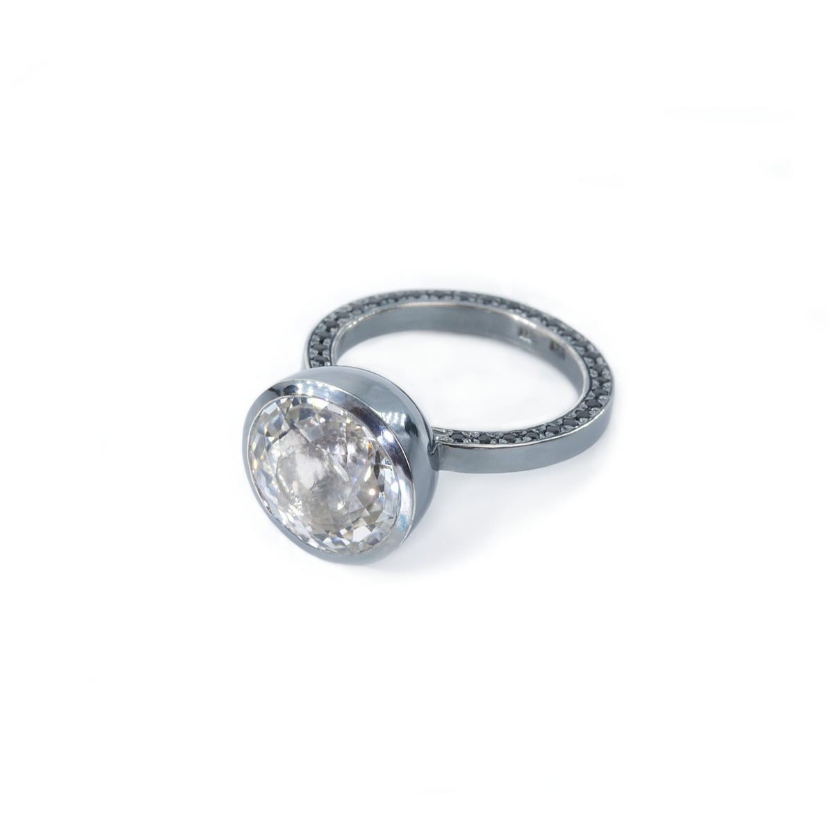 On a white background in the middle is placed ring with a huge white stone (topaz) as a focal. The shank of the ring is set with black stones (spinel). Ring is made by Ewa Z. Sleziona Jewellery. 