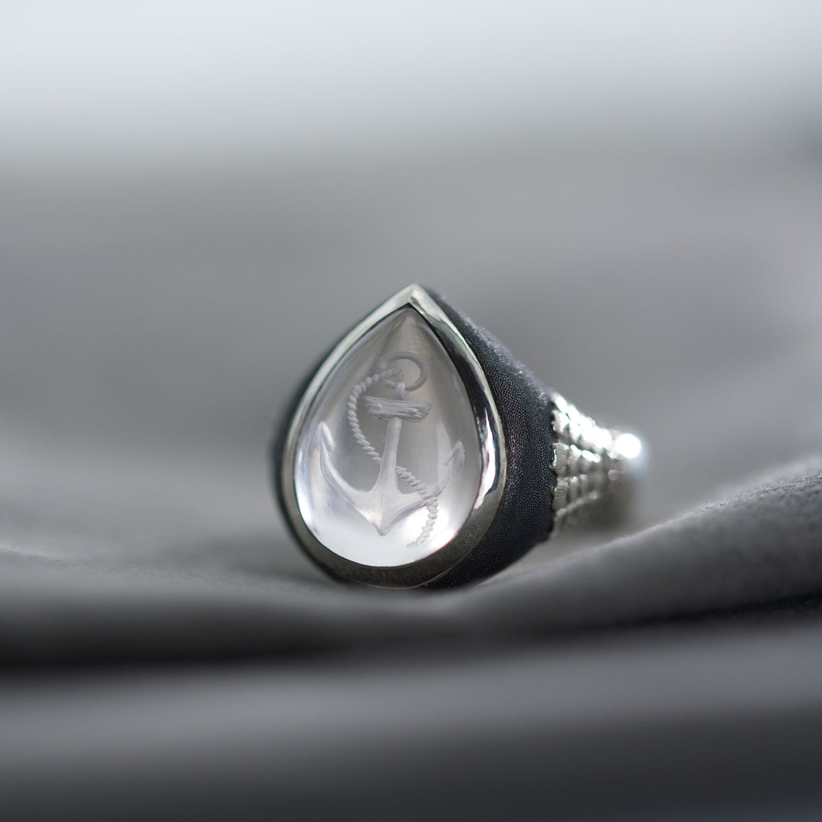 Silver ring with a teardrop-shaped design on a gray fabric background