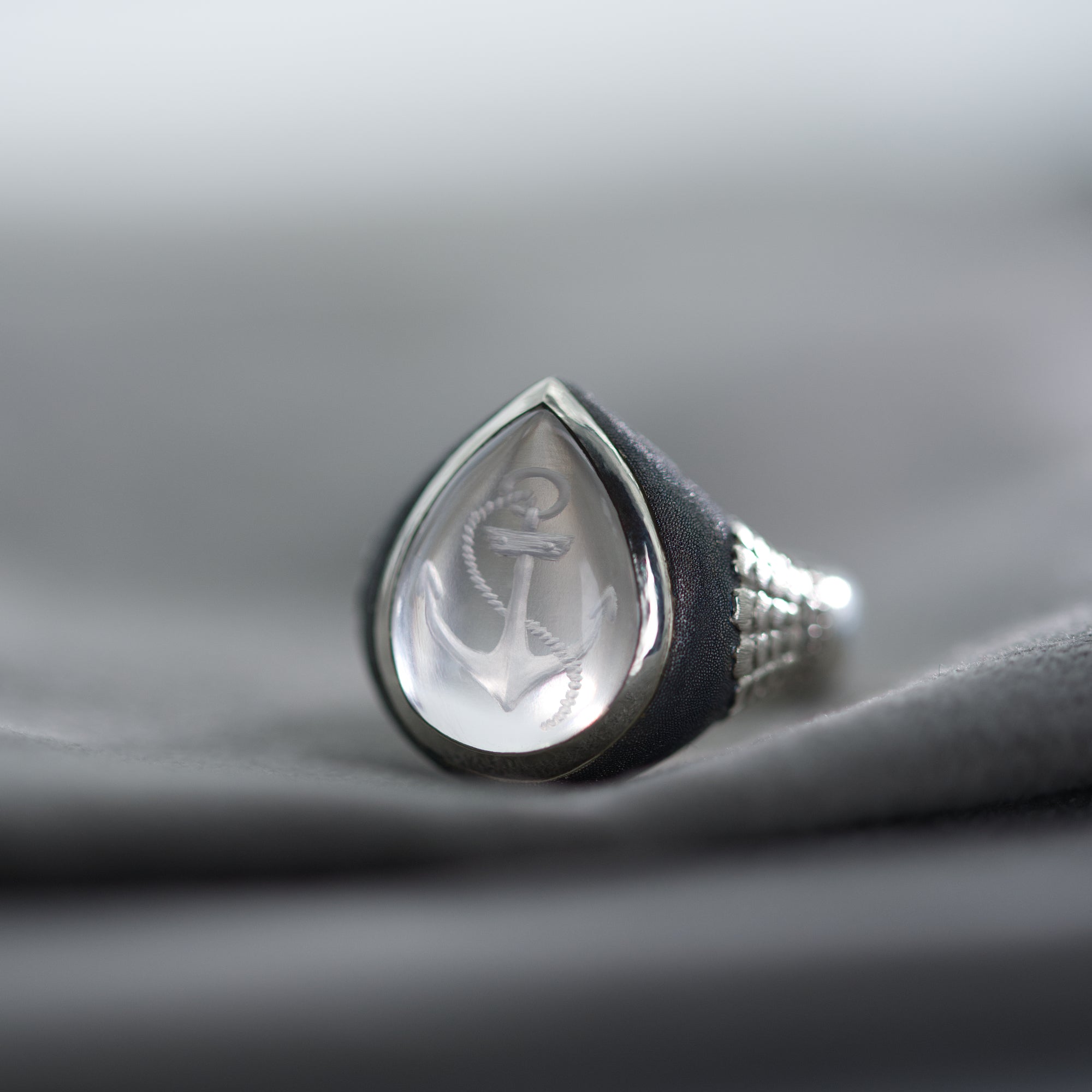 Silver ring with a teardrop-shaped design on a gray fabric background