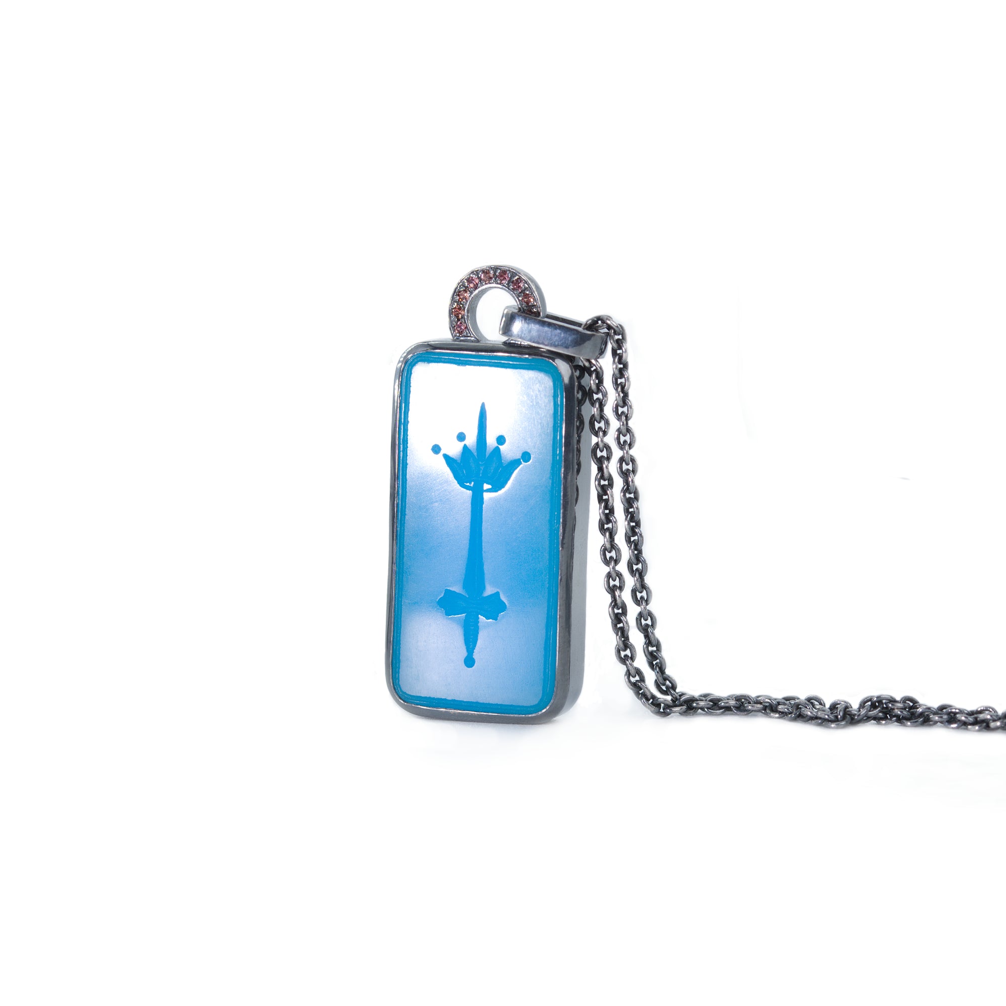 Intaglio necklace in blue featuring carved sword and crown. Pendant is adorned with peach-pink sapphires. the piece is made of blackened silver and showcased on white background.