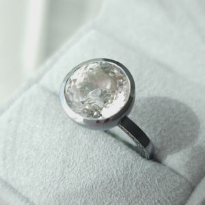 A short film showing a ring with huge white gem at the center and black stones set on the shank of the ring
