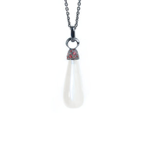 Moonstone necklace adorned with blackened silver cap with  red sapphires hanging from simple chain. Necklace showed on white background.