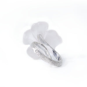 Photo shows a back of the white pansy flower ring carved in rock crystal and its silver band presented on white background.