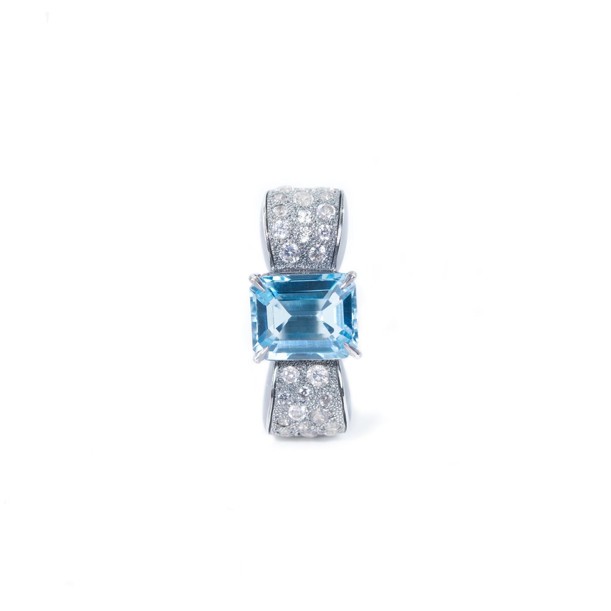 The photo shows the front view of the bow-shaped ring. In the center of the bow there is an octagonal blue topaz, the sides of the bow are decorated with round white zircons. The design of the ring is in the classic Art Deco style.