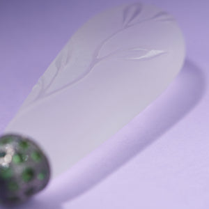 Necklace element on purple background shows leaves carved in gorse crystal. Necklace made by Ewa Z. Sleziona.