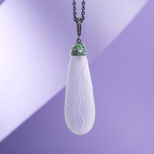 Necklace with carved leaves in rock crystal in the form of a drop is presented on a purple background. Necklace made by Ewa Z. Sleziona.