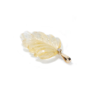 The photo features hand-carved citrine leaf pendant. The pendant is placed on the side to present the bail of the pendant which is made of 18K gold and finished with light brown diamond.