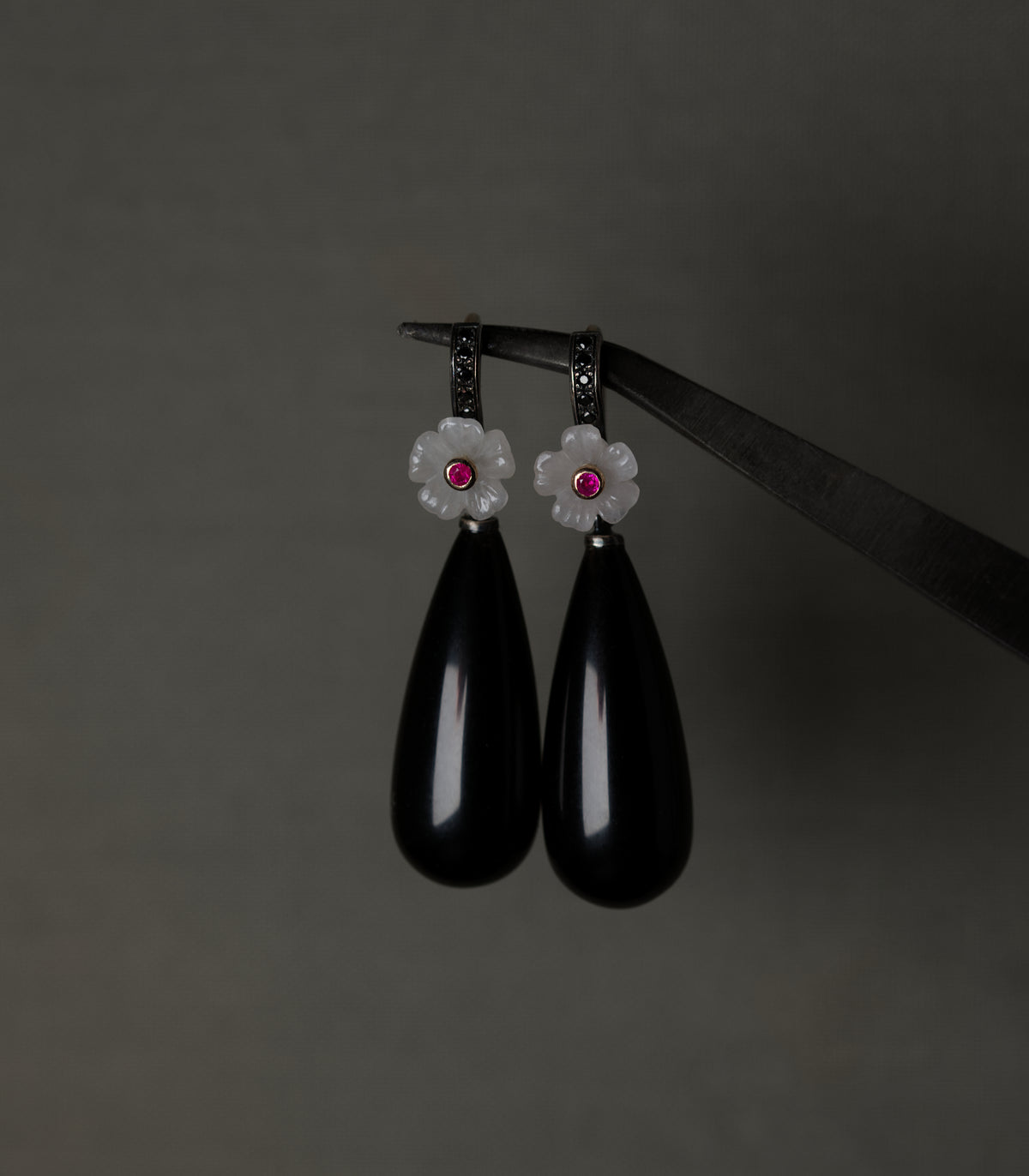 A pair of earrings with carved rose quartz flowers, ruby centres, and long polished obsidian drops.