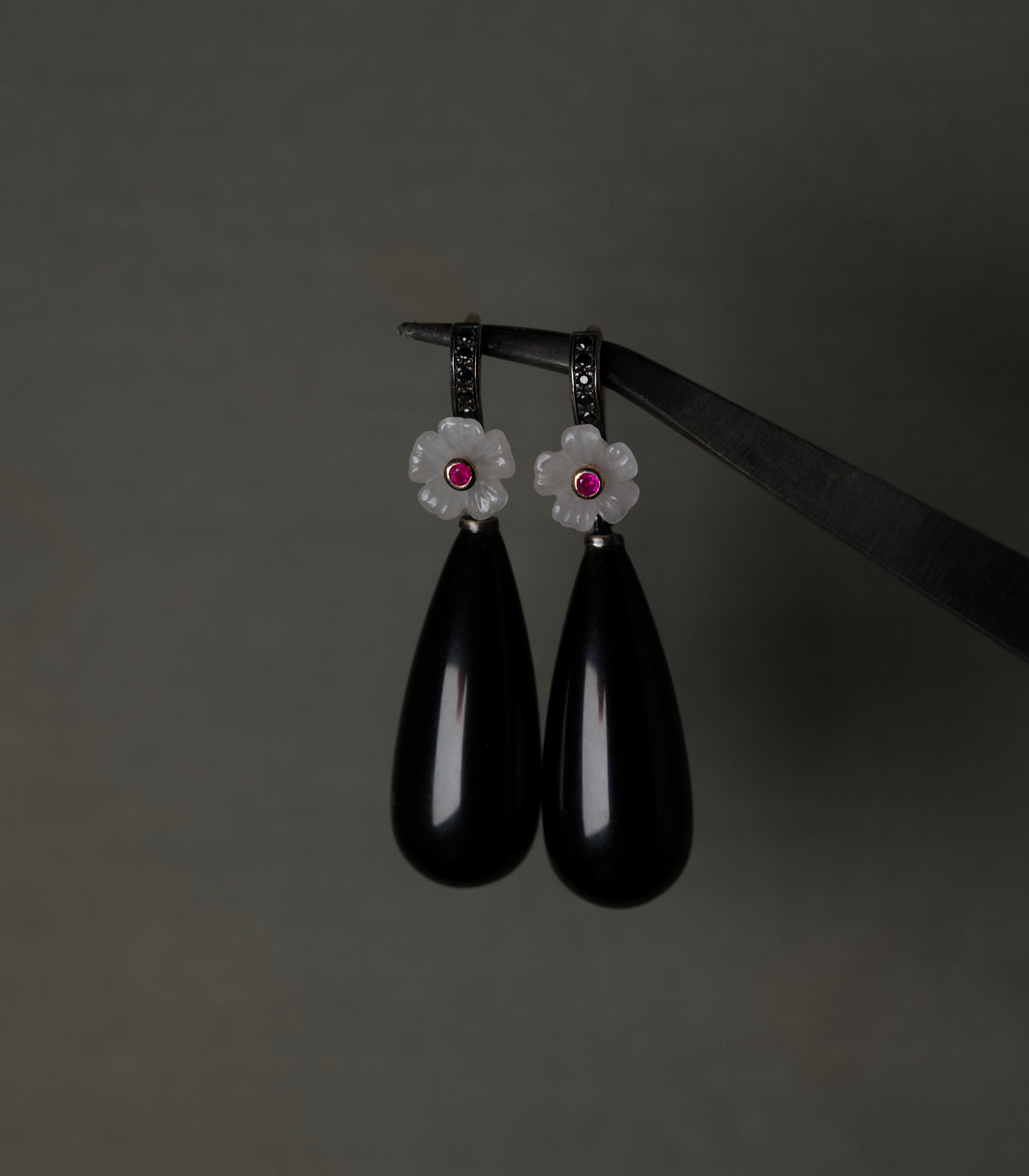 A pair of earrings with carved rose quartz flowers, ruby centres, and long polished obsidian drops.