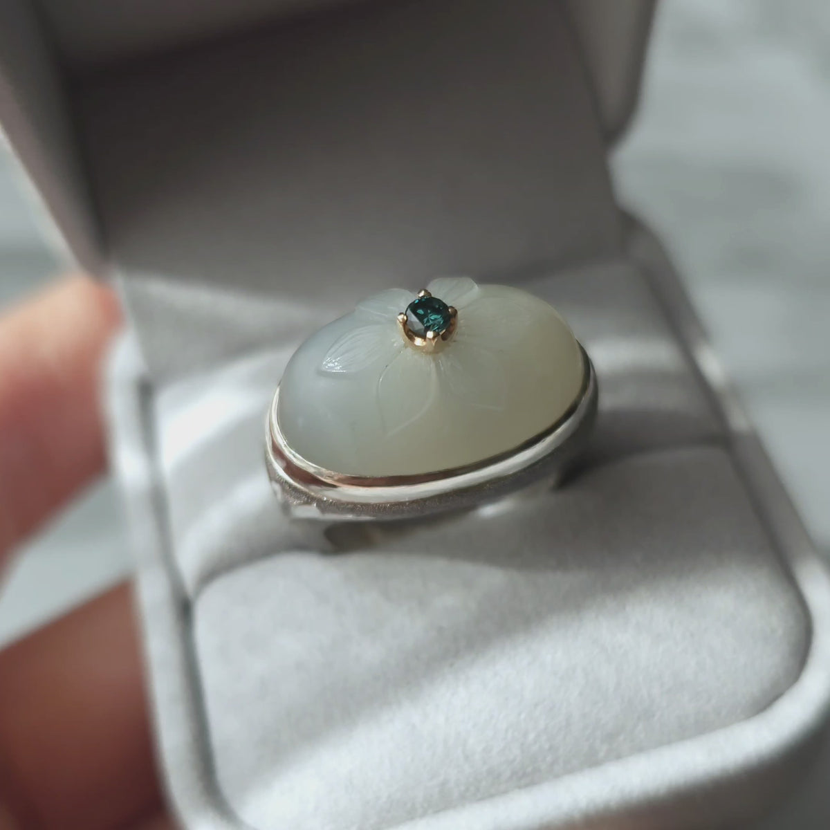 A short video presenting a ring with floral cameo , placed in grey jewellery box.