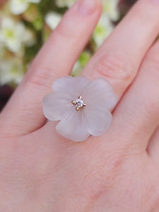 A short video presents a ring on a hand. Ring is composed of a flower carved from rock crystal and adorned with chocolate diamond.